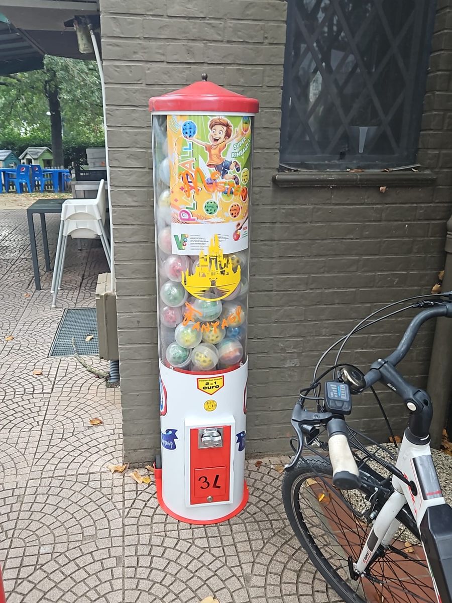 Colonna di distributori di palline installata all'esterno di un locale, accanto al muro